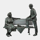 Giant Sculptures Life-Size Conversing Couple on Bench Bronze Sculpture 220cm, woman seated and bowler-hatted man leaning on bench, green-grey patina, plain background.