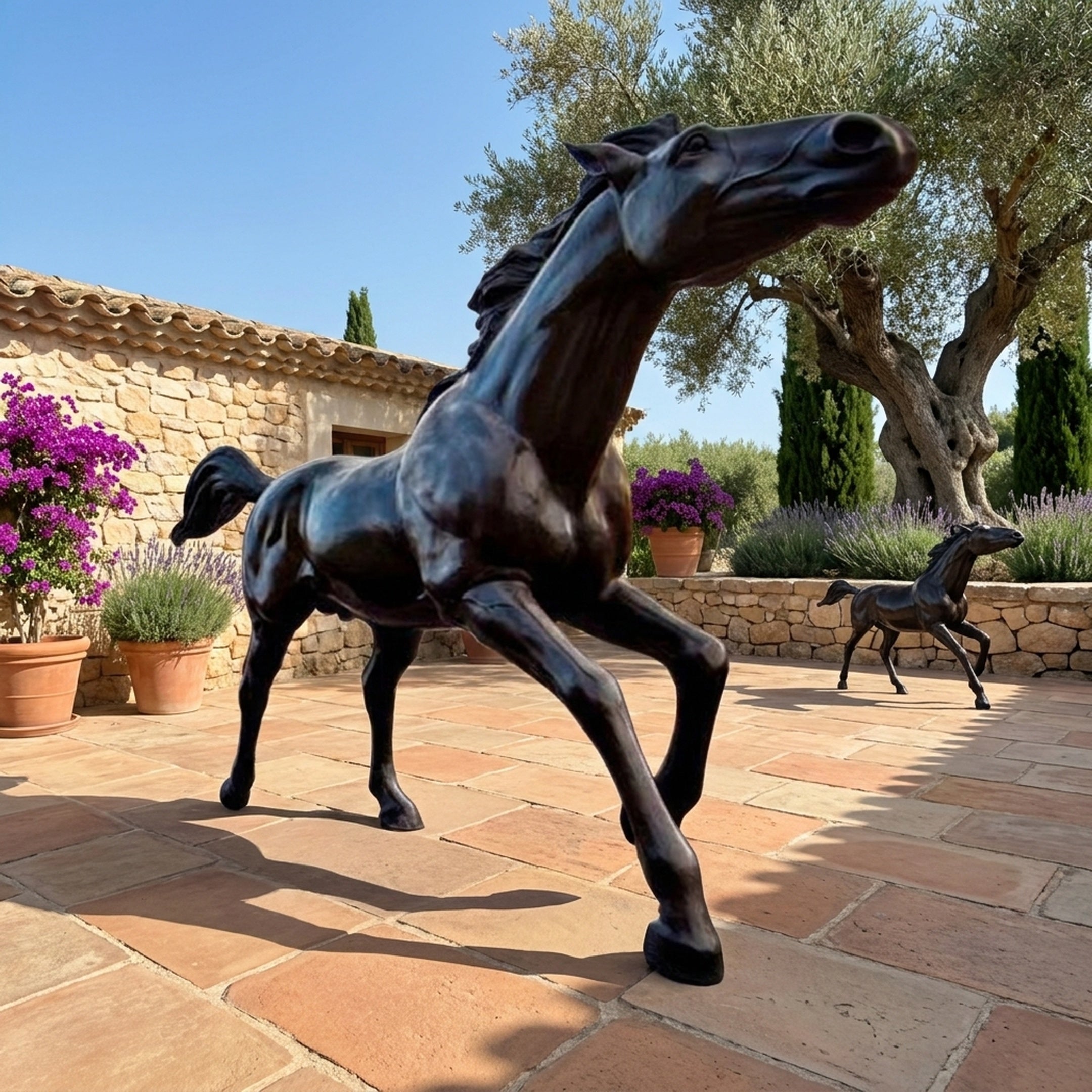 Life-Size Galloping Horse Bronze Sculpture by Giant Sculptures in dark patina, mid-stride on a terracotta terrace with olive trees, lavender, and a smaller foal sculpture behind.