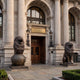 Giant Sculptures Life-Size Heraldic Roaring Lions Bronze Sculpture Pair flanking a grand columned entrance with arched wooden doors and stone facade.