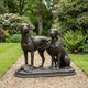 Life-Size Hunting Dogs Bronze Sculpture by Giant Sculptures on a gravel garden path, showing one standing and one seated hound with a game bird at their feet.