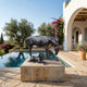 Life-Size Mare and Foal Bronze Sculpture by Giant Sculptures with dark patina, displayed on a travertine plinth beside a Mediterranean villa pool.
