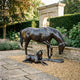 Life-Size Mare and Foal Bronze Sculpture by Giant Sculptures, dark patinated mare grazing beside recumbent foal on gravel in a stone garden with arched gateway.