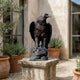 Giant Sculptures Life-Size Traditional Bald Eagle Bronze Sculpture with raised wings on a rocky base, displayed on a stone plinth in a Mediterranean courtyard.