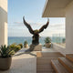 Life-Size Traditional Bald Eagle Bronze Sculpture by Giant Sculptures with wings spread on a pale plinth, displayed on an oceanfront terrace with agave planters.