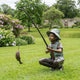 Giant Sculptures Life-Size Traditional Boy Fishing Bronze Sculpture on a lawn, boy crouched with verdigris hat and vest, rod arched, fish on the line.