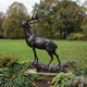Life-Size Traditional Bugling Bull Elk Bronze Sculpture by Giant Sculptures, head raised mid-call on a rocky base, set in a garden with autumn trees behind.
