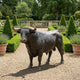 Life-Size Traditional Charging Bull Bronze Sculpture by Giant Sculptures with golden horn tips, standing on gravel in a formal garden with topiary and lavender.