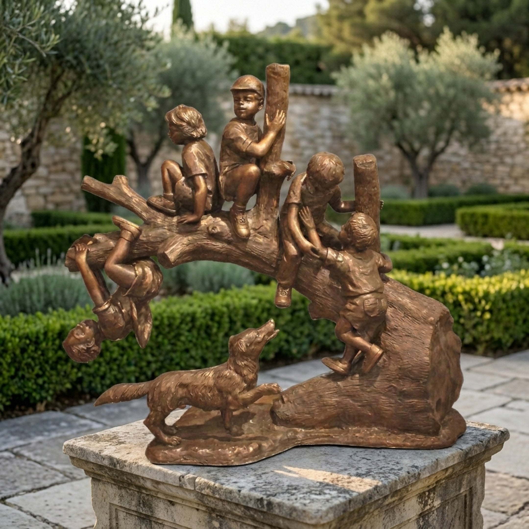 Life-Size Traditional Children Playing on a Tree Log Bronze Sculpture by Giant Sculptures, displayed on a stone plinth in a Mediterranean garden with olive trees.