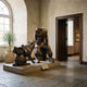 Life-Size Traditional Cowboy and Husky Dog Bronze Sculpture by Giant Sculptures, 190cm, shown in a stone-floored gallery beside an arched window and doorway.