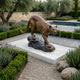Life-Size Traditional Crouching Cougar Bronze Sculpture by Giant Sculptures on a white marble plinth in a Mediterranean garden with lavender, olive trees, and pool.