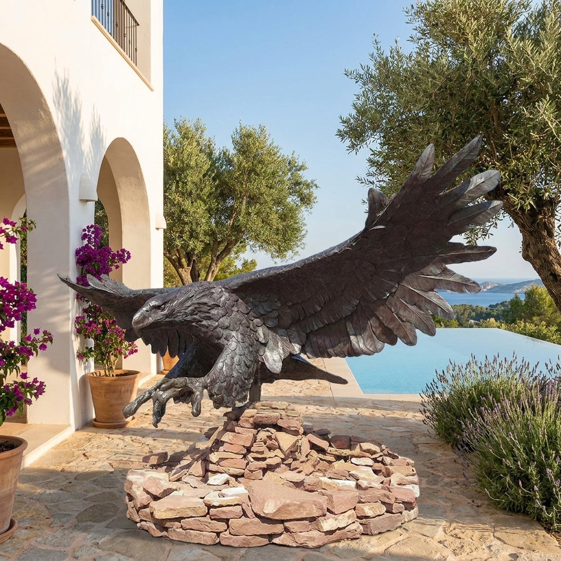 Life-Size Traditional Diving Strike Eagle Bronze Sculpture by Giant Sculptures on a stacked stone base, displayed on a Mediterranean terrace beside an infinity pool.