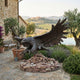 Life-Size Traditional Diving Strike Eagle Bronze Sculpture by Giant Sculptures on a stacked stone base in a Tuscan courtyard with olive trees and hills.