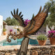 Life-Size Traditional Eagle Bronze Sculpture by Giant Sculptures, wings raised mid-strike with a coiled serpent in its talons, displayed beside a poolside terrace.