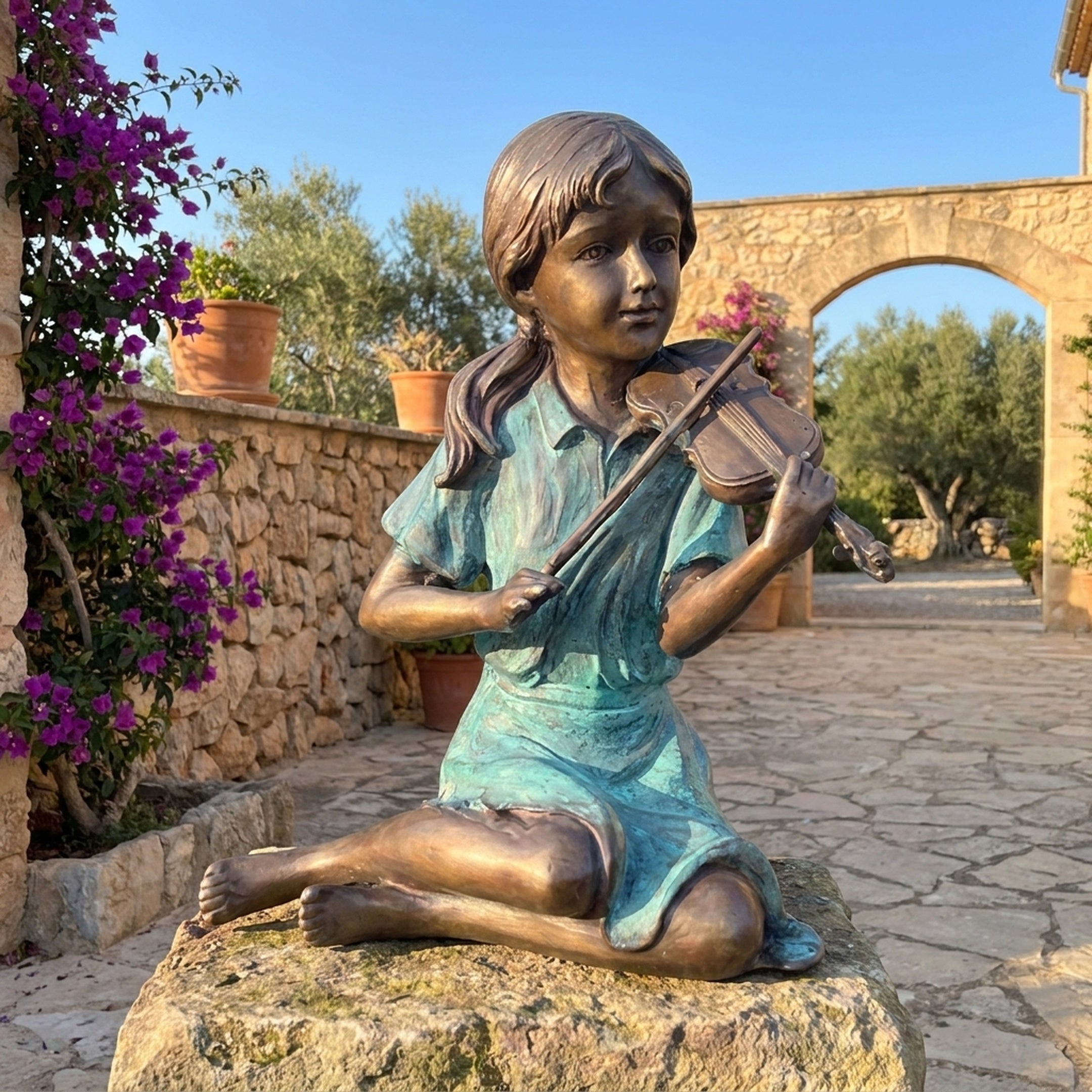 Life-Size Traditional Girl Playing Violin Bronze Sculpture by Giant Sculptures, seated on stone with two-tone turquoise dress and bronze skin, in a sunlit courtyard.