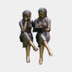 Life-Size Traditional Girls on Bench Bronze Sculpture by Giant Sculptures, showing two barefoot girls seated together as one writes in a book.