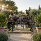 Life-size bronze sculpture by Giant Sculptures showing grandparents and two grandchildren seated on a bench in a Mediterranean garden with lemon trees and lavender.