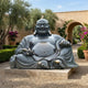 Life-Size Traditional Laughing Buddha Bronze Sculpture by Giant Sculptures, dark patina with gilt highlights on a carved stone plinth in a Mediterranean garden.