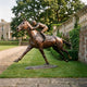 Life-Size Traditional Racing Horse and Jockey Bronze Sculpture from Giant Sculptures shown at full gallop on a lawn beside a balustrade and country estate.