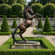 Life-Size Traditional Rearing Horse Bronze Sculpture by Giant Sculptures, reddish-brown patina, displayed on a stone plinth in a formal garden with lavender and topiary.