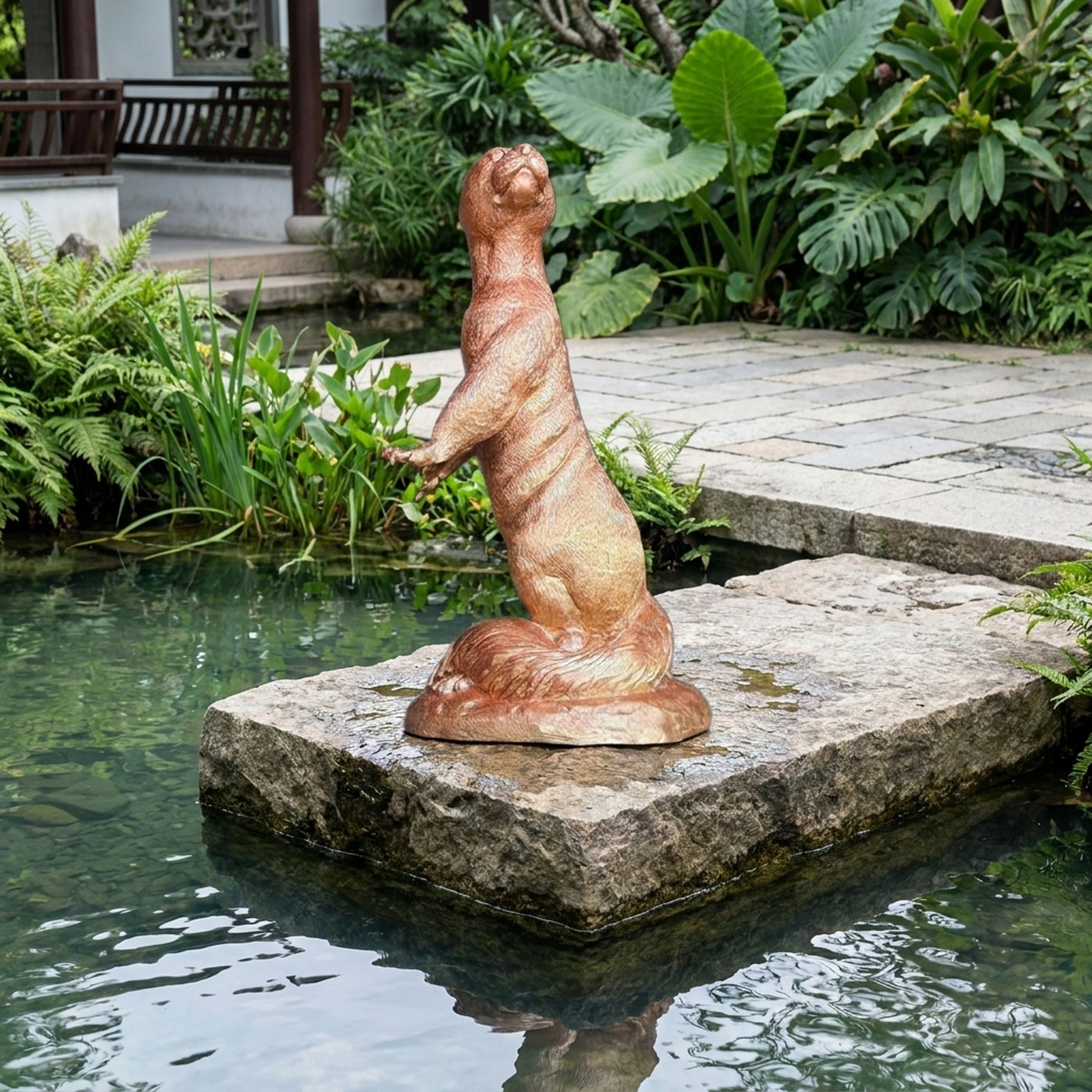 Life-Size Traditional Rearing Otter Bronze Sculpture by Giant Sculptures with warm copper patina, displayed on a stone slab beside a garden pond.