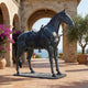 Life-Size Traditional Saddled Horse Bronze Sculpture by Giant Sculptures, 180cm, shown side-on with Western saddle and bridle on a Mediterranean stone terrace.