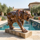 Life-Size Traditional Stalking Tiger Bronze Sculpture by Giant Sculptures on a stone plinth beside a pool, with olive trees and a Mediterranean villa behind.