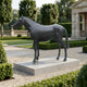 Life-Size Traditional Standing Horse Bronze Sculpture by Giant Sculptures with dark patina, displayed on a pale stone plinth in a formal hedged garden.