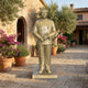 Life-Size Traditional Standing Male Figure Bronze Statue in warm gold patina by Giant Sculptures, displayed on a stone courtyard beside potted lavender and olive trees.