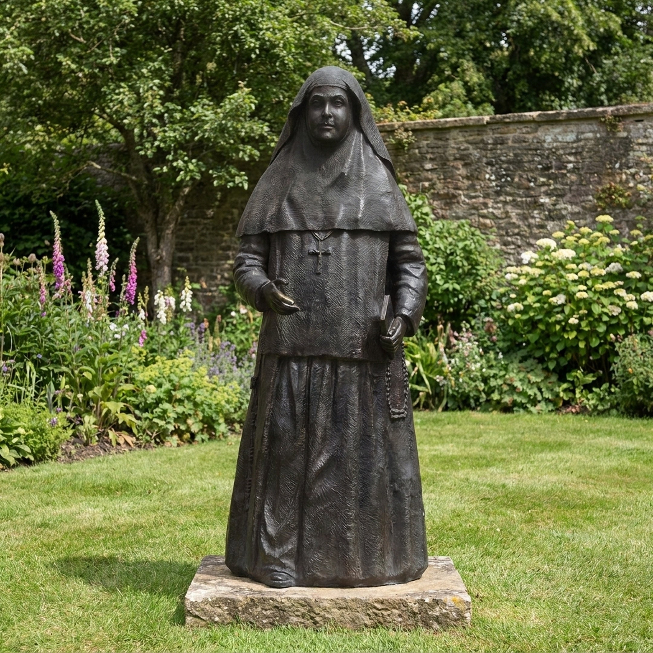 Life-Size Traditional Standing Nun Bronze Statue by Giant Sculptures, dark patina figure in habit and veil holding a book, set on a stone plinth in a garden.