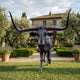Life-Size Traditional Texas Longhorn Bull Bronze Sculpture by Giant Sculptures shown front-on with wide horns, set on a lawn before a Tuscan villa garden.
