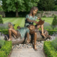 Life-Size Traditional Two Children Bronze Sculpture by Giant Sculptures on a log, older girl reading aloud while a younger child reclines across her lap in a garden.