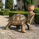 Life-Size Traditional Walking Tortoise Bronze Sculpture by Giant Sculptures, shown mid-stride with golden-brown patina on a stone terrace beside a Tuscan villa.