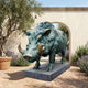 Life-Size Traditional Wild Boar Bronze Sculpture by Giant Sculptures with verdigris patina and golden tusks, on granite plinth in a Mediterranean courtyard.