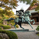 Giant Sculptures Monumental Armoured Samurai Warrior and Horse Bronze Sculpture in verdigris patina, mid-gallop, displayed in a Japanese garden by a temple.