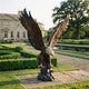 Monumental Bald Eagle Bronze Sculpture by Giant Sculptures at 240cm, wings raised in landing pose on a rocky base, displayed on a manor garden terrace.