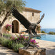 Monumental Bald Eagle Bronze Sculpture by Giant Sculptures, wings raised mid-landing on a branch perch, beside an infinity pool at a Mediterranean villa.