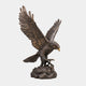 Monumental Bald Eagle Bronze Sculpture by Giant Sculptures shown with wings raised mid-landing, talons gripping a rocky base, against a plain light background.