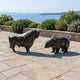 Monumental Bull and Bear Bronze Sculpture Set by Giant Sculptures in near-black patina, displayed facing each other on a stone terrace overlooking the sea.