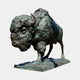 Monumental Charging Bison Bronze Sculpture by Giant Sculptures, shown in three-quarter view with lowered head, textured green-blue verdigris patina, on a stone base.