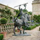 Monumental Classical Armoured Warrior on Rearing Horse Bronze Sculpture by Giant Sculptures, dark antique patina, displayed on a stone garden path beside roses.