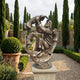 Monumental Classical Bearded Figure with Children Bronze Sculpture by Giant Sculptures on a stone plinth in a formal garden lined with cypress trees.