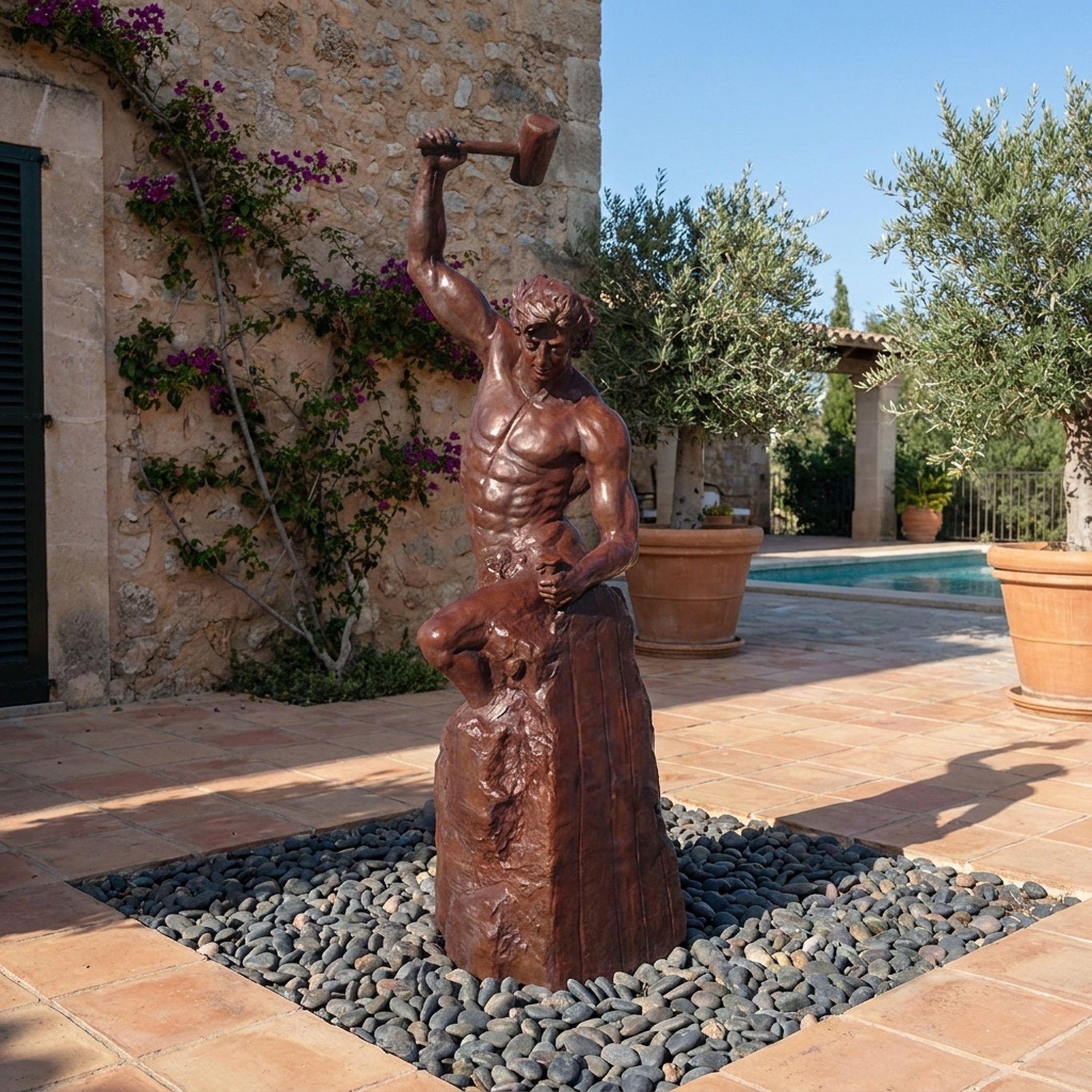 Monumental Classical Blacksmith Bronze Sculpture by Giant Sculptures, 240cm figure raising a mallet, displayed on pebbles in a Mediterranean poolside courtyard.