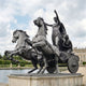 Monumental Classical Chariot with Goddess and Horses Bronze Sculpture by Giant Sculptures, dark patina, two rearing horses and standing figure, on stone plinth beside a reflecting pool.