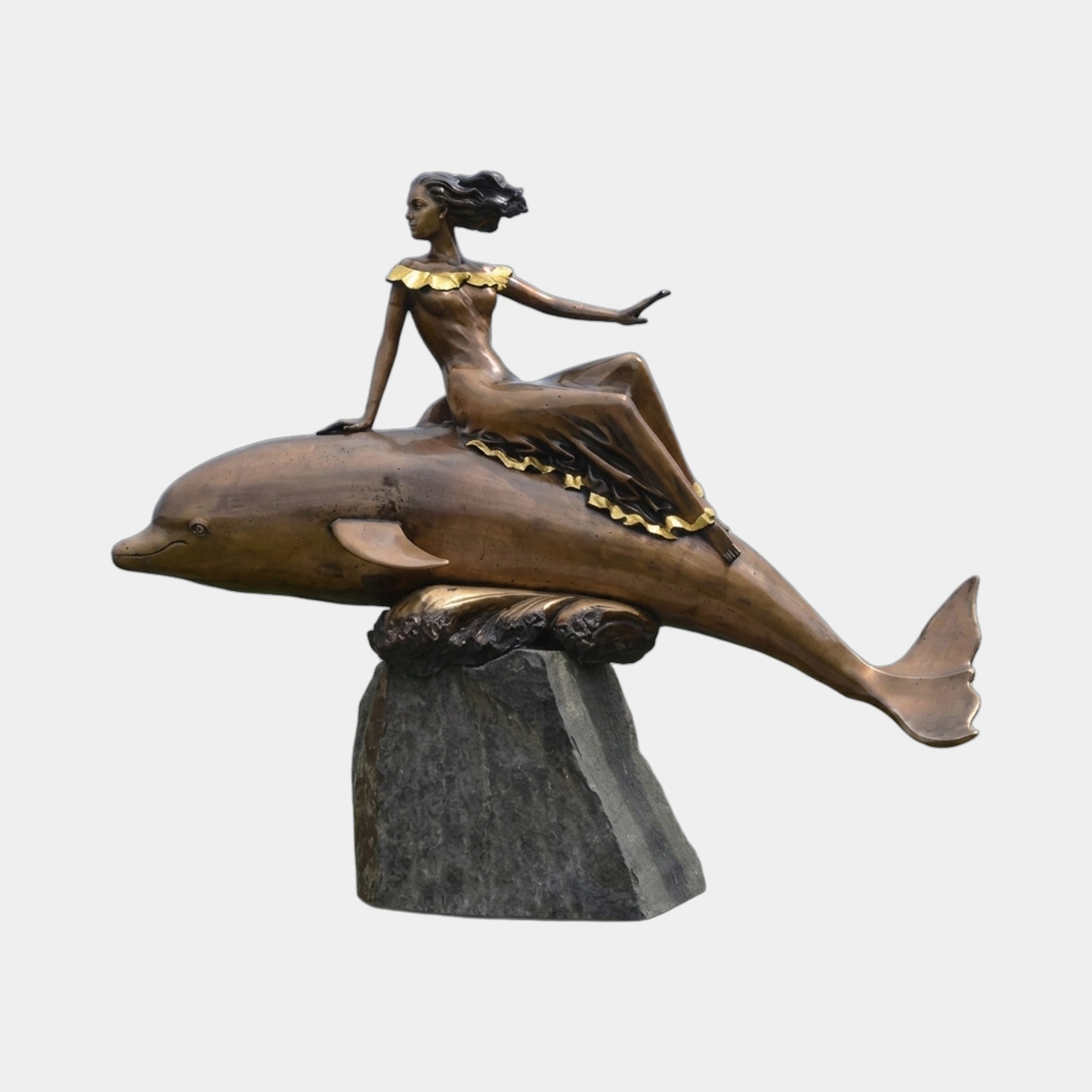 Monumental Classical Female Figure on Dolphin Bronze Sculpture by Giant Sculptures, side view with gold-accented skirt, on rough stone plinth, plain background.
