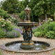 Monumental Classical Female Figures and Cherubs Bronze Fountain by Giant Sculptures, three-tiered with verdigris and gold patina, in a walled garden with roses and lavender.