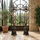 Monumental Classical Goddess Candelabra Bronze Sculpture Pair 210cm by Giant Sculptures, two-tone bronze figures holding nine-arm candelabras in an arched conservatory.