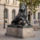 Giant Sculptures Monumental Classical Guardian Lion Bronze Sculpture 250cm with dark patina, paw on sphere, on stone plinth outside a classical building.