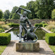 Monumental Classical Hero and Dragon Bronze Sculpture by Giant Sculptures, 250cm, verdigris patina, on stone plinth beside a formal garden pond.