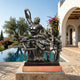 Monumental Classical Laocoön and Sons Bronze Sculpture by Giant Sculptures, dark patinated group entwined with serpents, displayed on a terrace beside a pool.