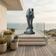 Monumental Classical Mermaid and Dolphin Bronze Sculpture by Giant Sculptures with verdigris patina, displayed on a glass-railed coastal terrace overlooking the sea.
